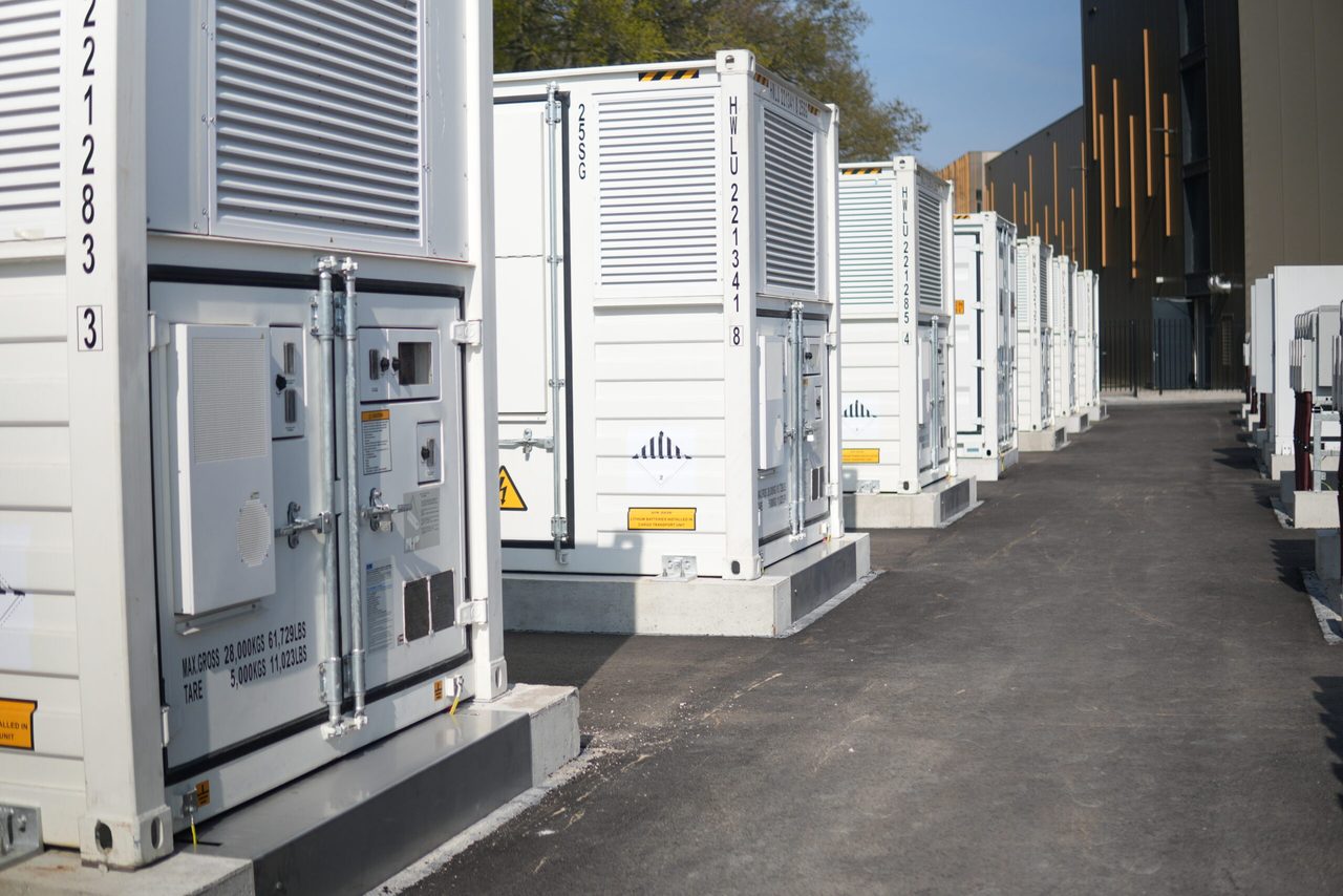 Row of containerised battery storage units between buildings