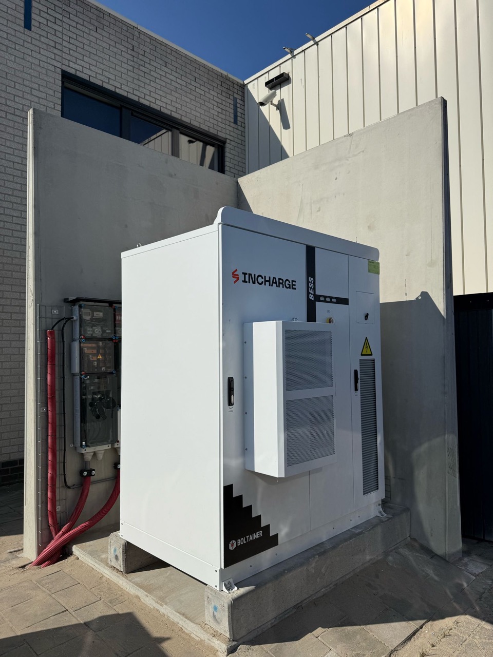 Battery storage cabinet within a concrete enclosure beside a building