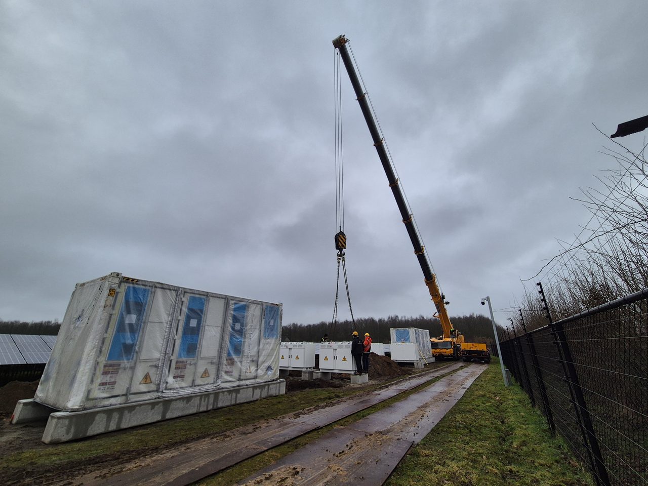 Crane positioning a battery storage container on site