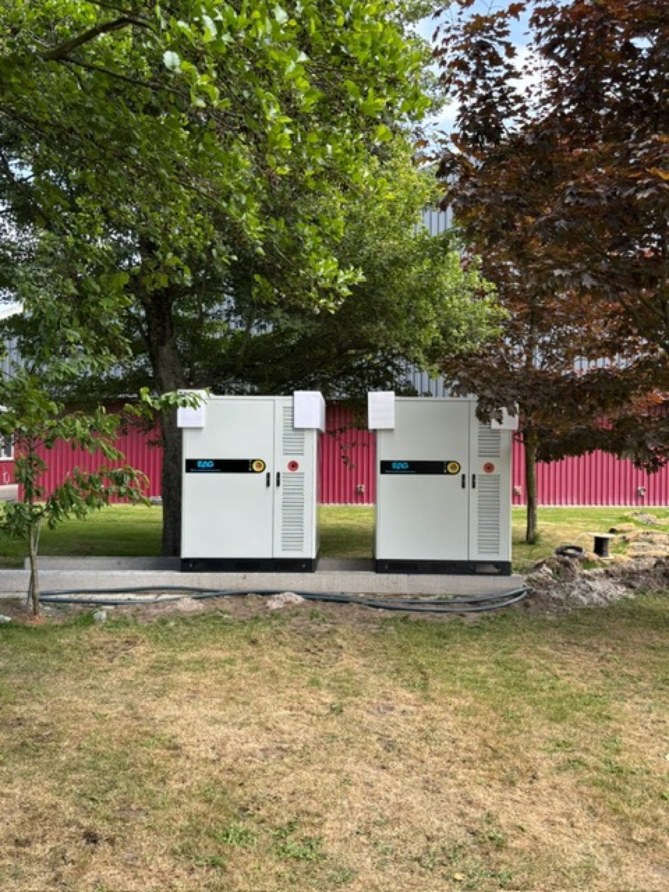 Two battery storage cabinets installed on a landscaped site